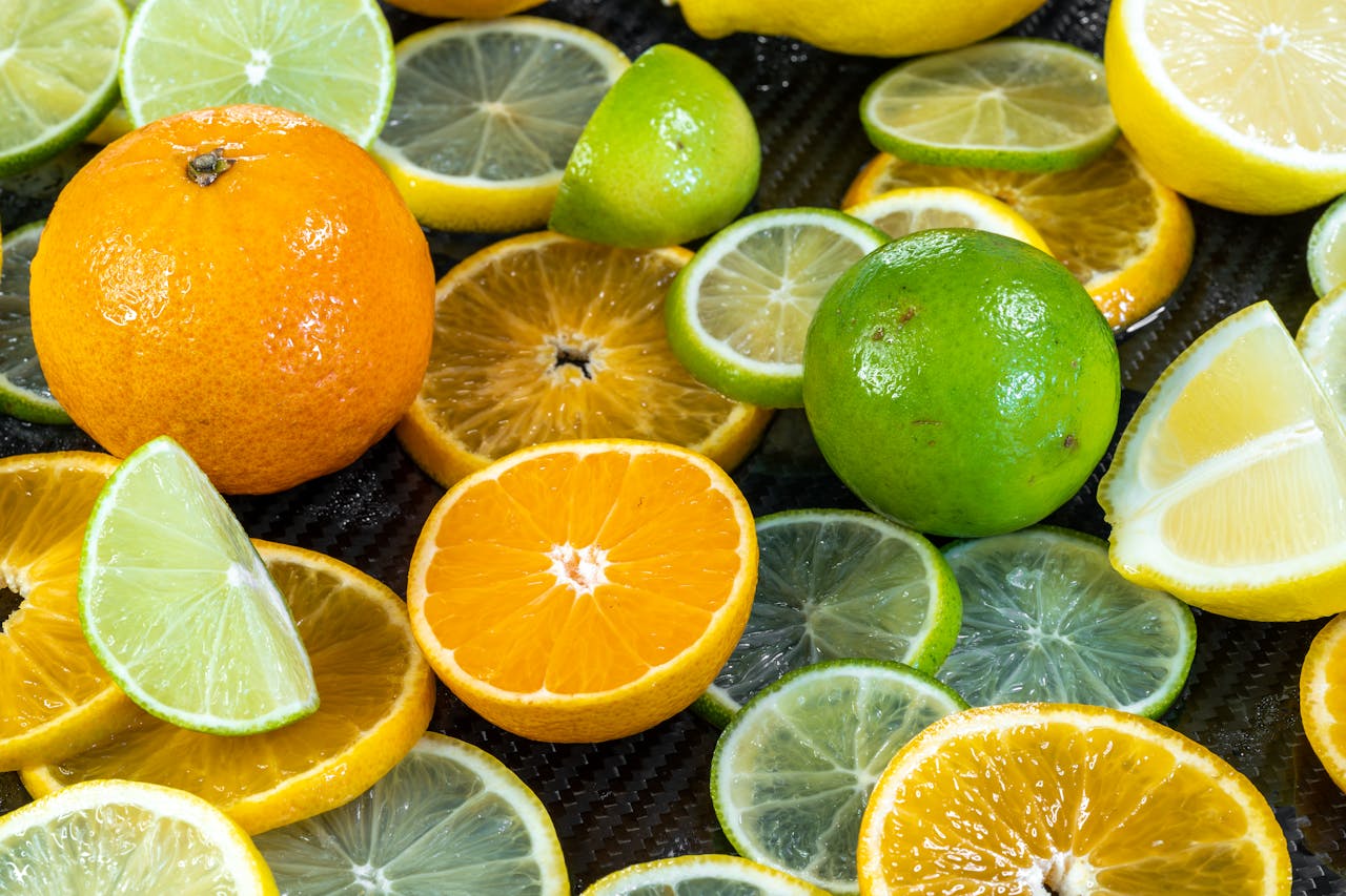 A colorful display of sliced and whole citrus fruits including oranges, lemons, and limes.
